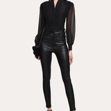 Woman wearing a black outfit with sheer sleeves on a white background