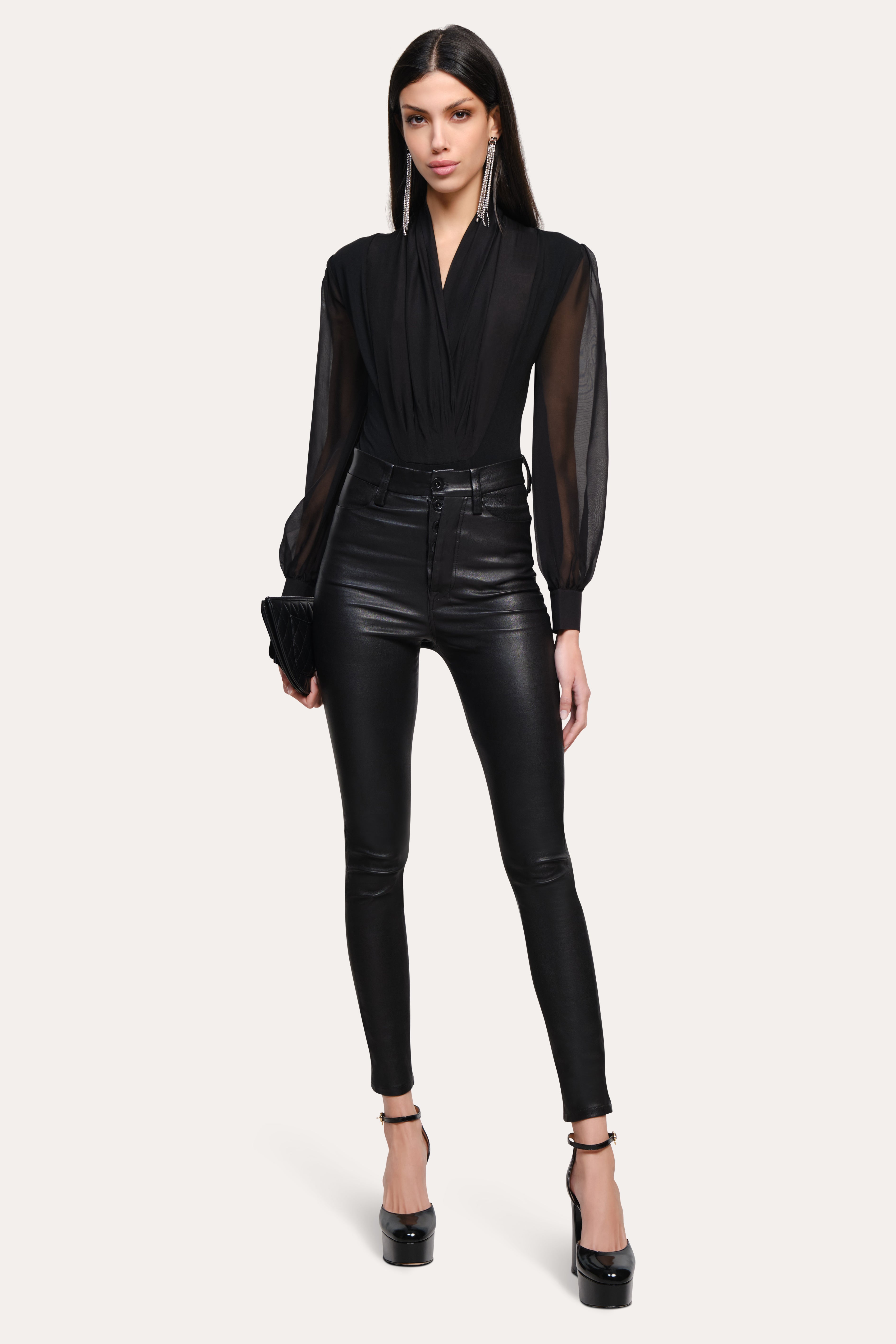 Woman wearing a black outfit with sheer sleeves on a white background